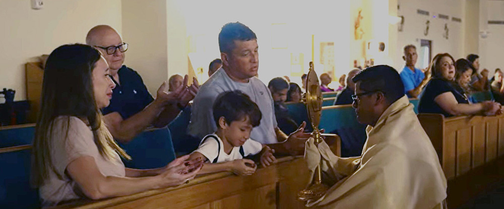 A family at St. Andrew Catholic Church in Coral Springs, Fla., prays before the Eucharist as Father Milton Jos&eacute; Mart&iacute;nez, vocations director for the Archdiocese of Miami and brother Knight, kneels with the monstrance.