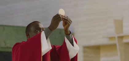 A priest celebrating Mass raises the host.