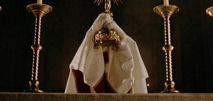 A priest raises the Blessed Sacrament in a monstrance.