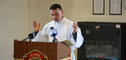 Father Juan Manuel Camacho, pastor of St. Lucy Catholic Church in Racine, Wis., prays a blessing over the new Safe Haven Baby Box installed behind him at the city’s Fire Station 4. 