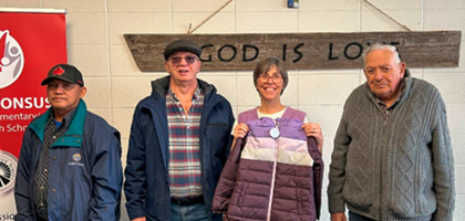 Knights from St. Christopher Council 4788 in Edmonton, Alberta, present a coat to Michelle Wilson, principal of St. Alphonsus Catholic School. The council donated 120 coats through the Knights of Columbus Coats for Kids program to five inner-city Catholic elementary schools. The Knights have participated in the program for the past 10 years, donating more than 1,000 coats to children in need.