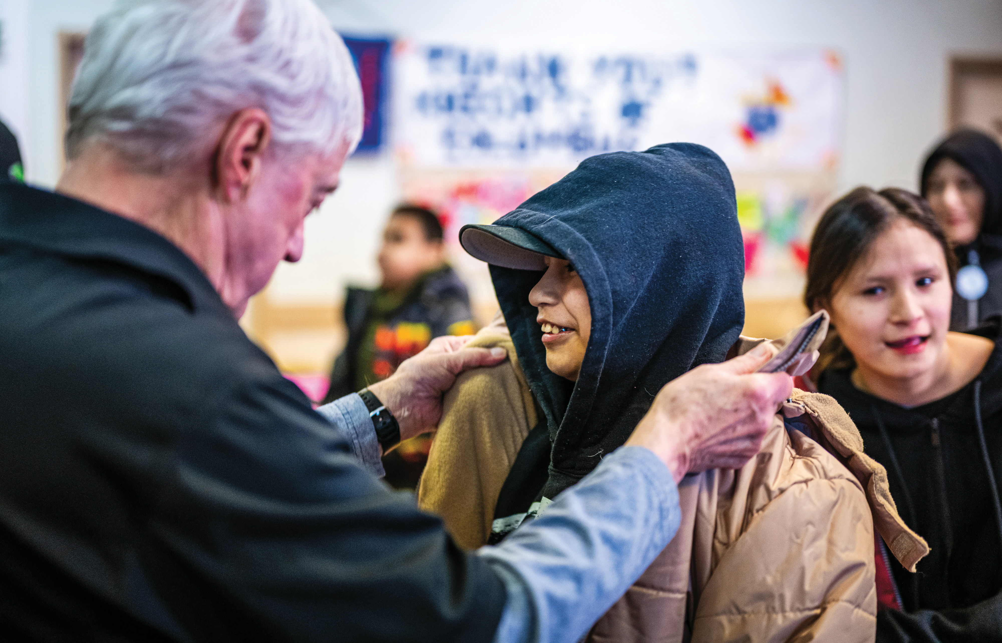 District Deputy Vaughn Wadelius helps a child into a new coat during the distribution in the parish hall of Sacred Heart Church.