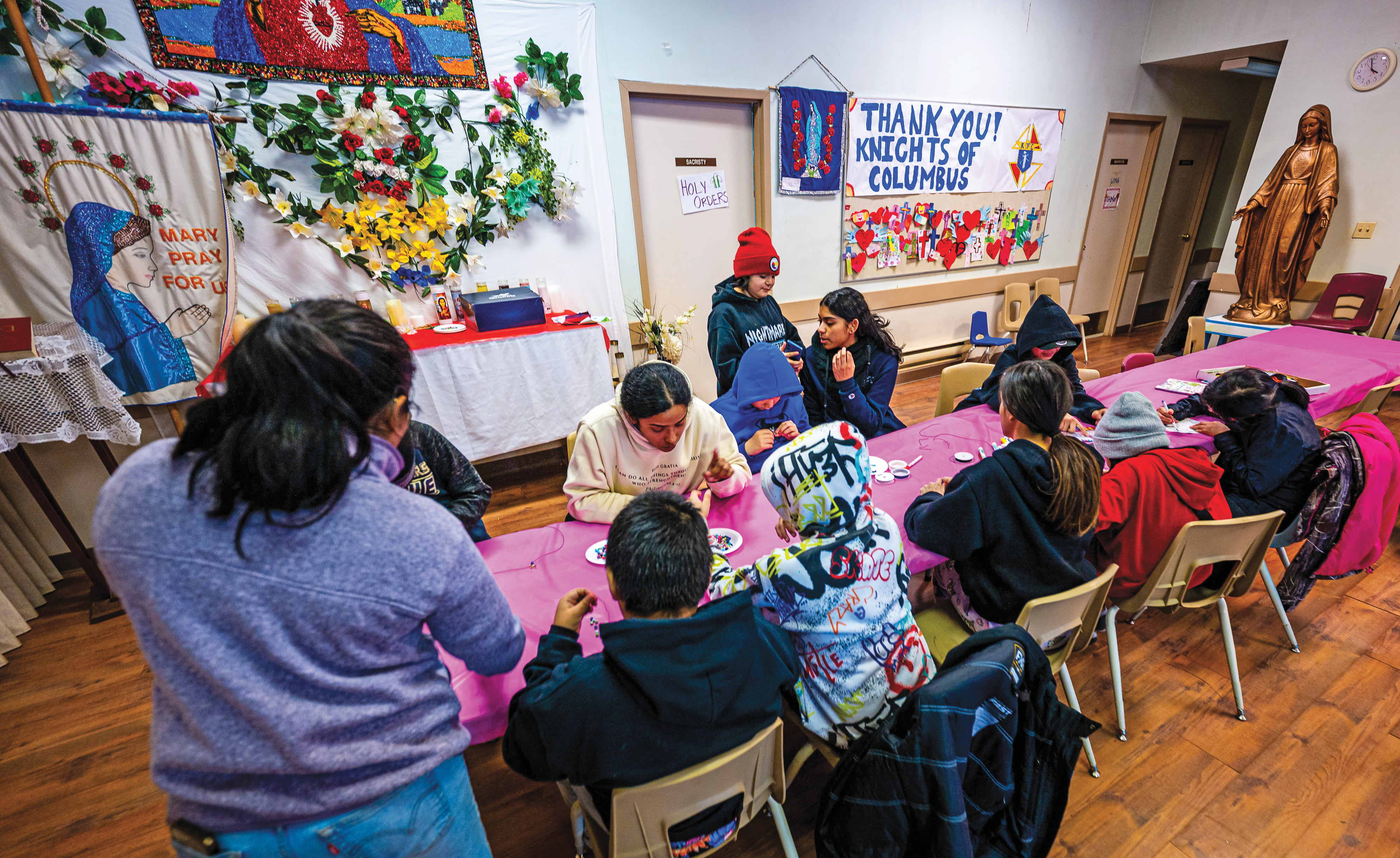 Children complete arts and crafts as they wait for winter jackets to be distributed by the Knights at Sacred Heart Church.