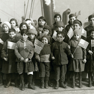 A group of Jewish children orphaned as a result of World War I pose with U.S. flags after arriving to New York City in 1921