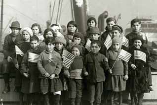 A group of Jewish children orphaned as a result of World War I pose with U.S. flags after arriving to New York City in 1921