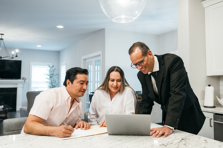 Smiling insurance agent presenting finances to couple at kitchen counter
