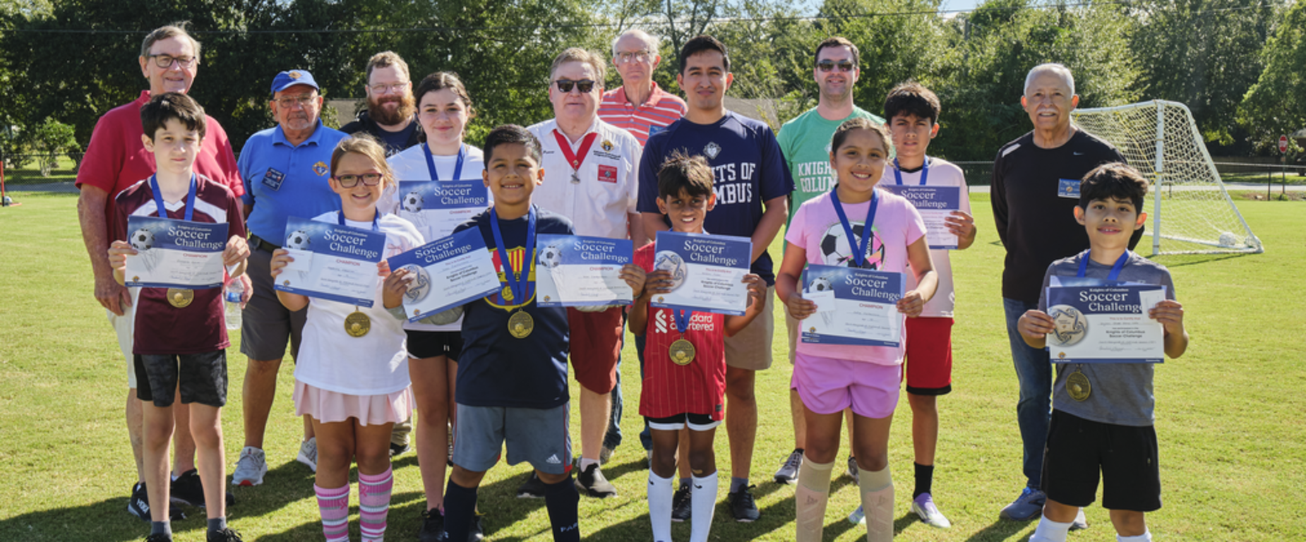A group of people posing for a photo on a soccer field.