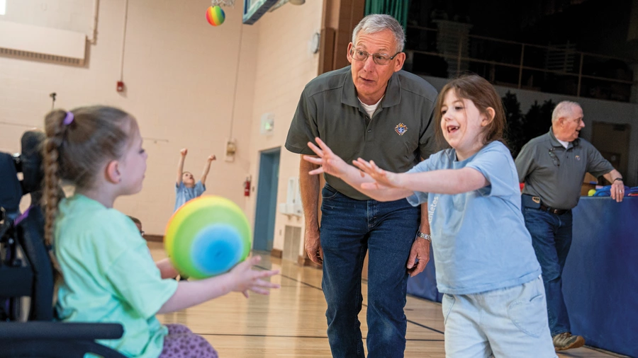 A Knight encourages two girls participating in the Special Olympics Young Athletes program
