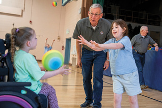 A Knight encourages two girls participating in the Special Olympics Young Athletes program