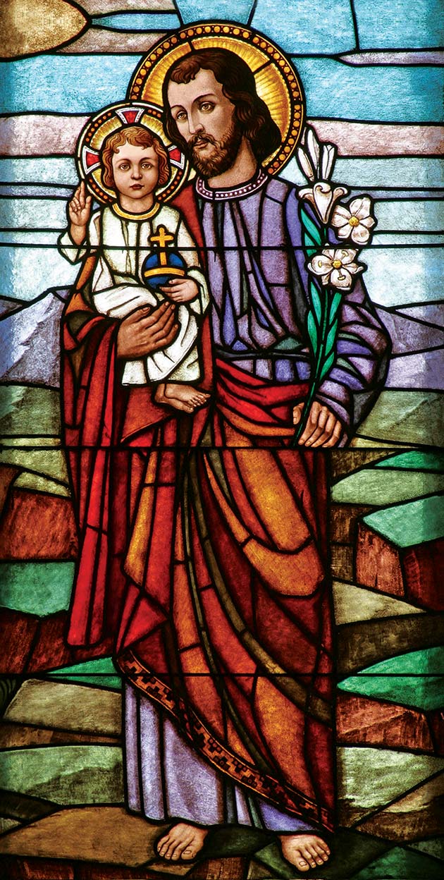 Stained glass image of St. Joseph holding child Jesus.