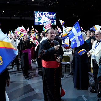 Flags wave as Cardinal Gérald Lacroix, archbishop of Québec, and other dais guests process into the States Dinner of the 142nd Supreme Convention on Aug. 6.