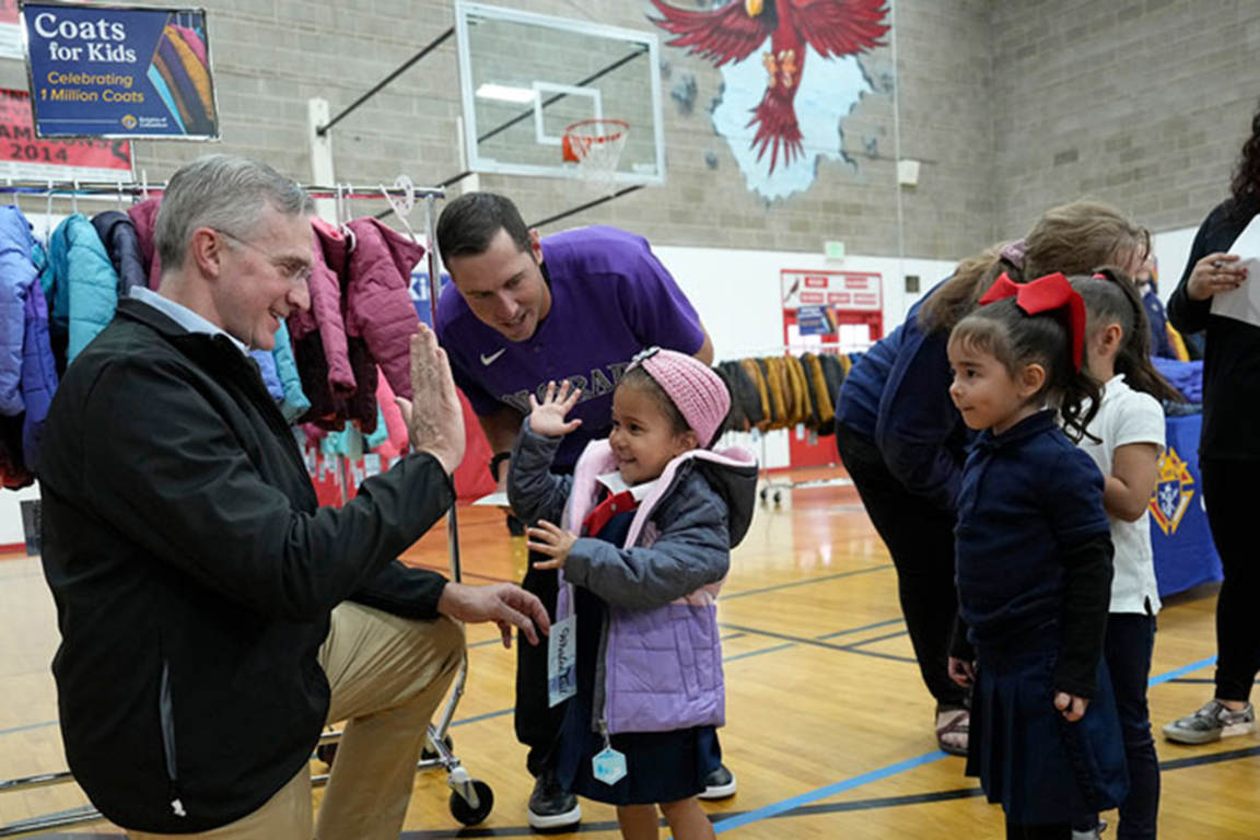 Supreme Knight with a child who received a coat from Knights of Columbus.