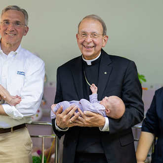 Supreme Knight Patrick Kelly and Supreme Chaplain Archbishop William Lori, joined by Daughters of Charity Sister Denise Abu Haider, hold infant residents of the sisters’ Holy Family Children’s Home in Bethlehem. (Photo by George Jaraiseh)