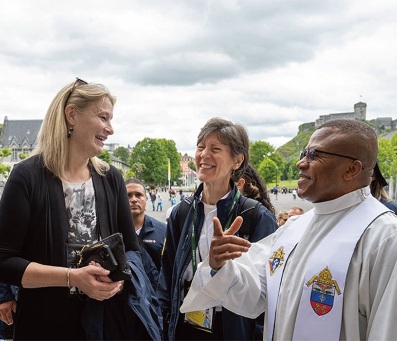 Charna Seibert speak with a priest during the Warriors to Lourdes pilgrimage in May 2024.