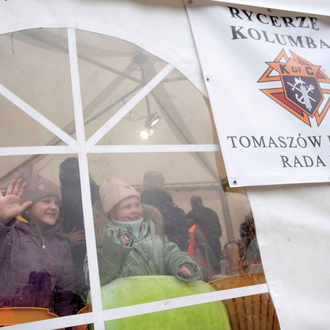 Ukrainian girls wave from inside a heated tent at the K of C Mercy Center in Hrebenne, Poland