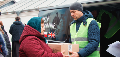 Ivan Kubiak, a member of St. Apostle John the Theologian Council 18626 in Sharhorod gives a box of food to the mother of a fallen Ukrainian soldier after an interconfessional prayer service for Christian unity and peace at St. Florian Parish.