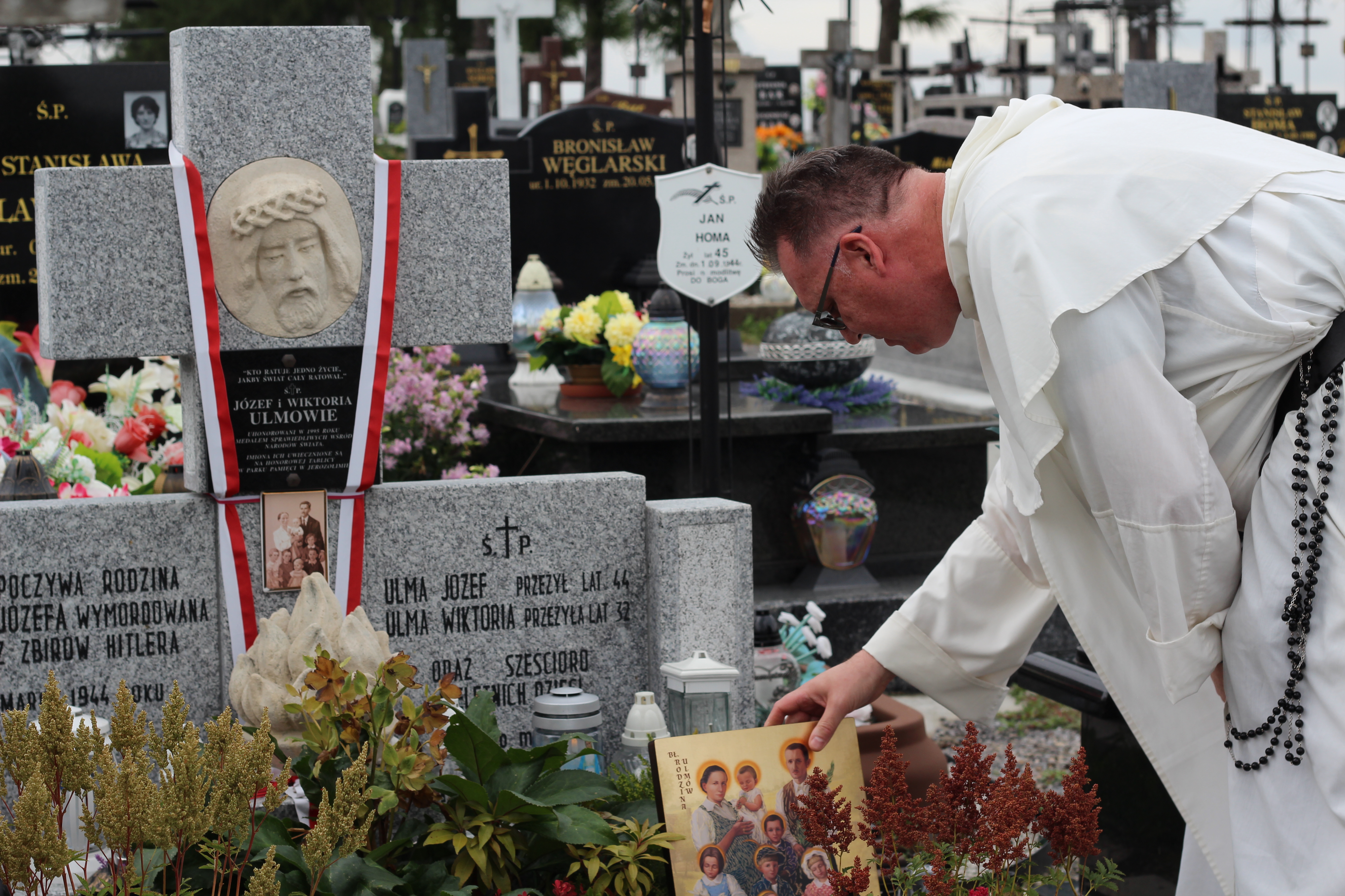 Dominican Father Jonathan Kalisch, director of chaplains and spiritual development, places an icon of the Ulma family at their burial site at St. Dorothy Parish Cemetery in Markowa, Poland.