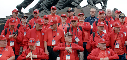 Veterans wearing matching shirts in front of the statue of Marine Corps War Memorial