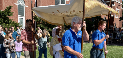 Father Joe Sellas, pastor of Holy Trinity Church and chaplain of Paola (Kan.) Council 1149, carries the monstrance as Knights hold the canopy during a Corpus Christi procession around the parish campus. About 350 parishioners joined the procession, which concluded with the celebration of Mass.
