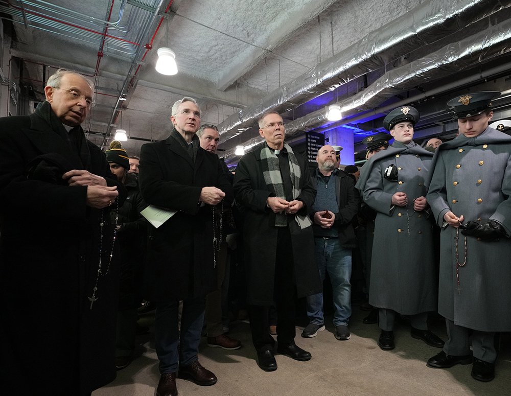 Supreme Chaplain Archbishop William Lori (left) and Supreme Knight Patrick Kelly pray the rosary with cadets from the U.S. Military Academy and midshipmen from the U.S. Naval Academy during halftime at the 126th Army-Navy football game in Baltimore on Dec. 13. (Photo by Paul Haring))