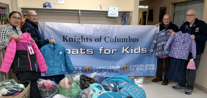 Knights from Louis Hebert Council 6468 in Moncton, New Brunswick, and Margaret Estandarte, administrative assistant at Moncton Headstart, display some of the more than 60 pieces of winter clothing donated by Council 6468 to the charity. 