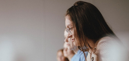 Group of women listening while the woman in front hold a paint brush.
