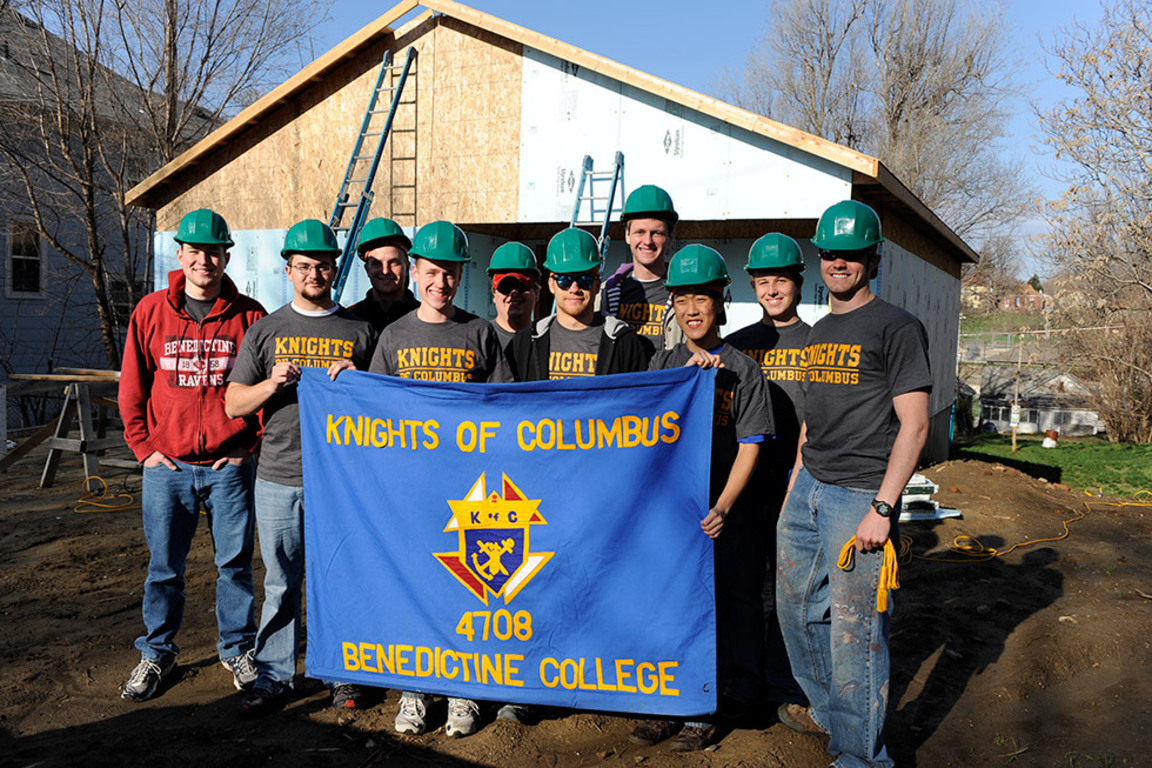 Young Knights from council 4708 engaged in a housing project pausing for a photo holding their banner.