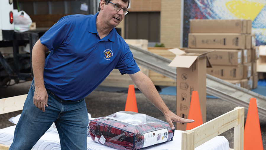 Grand Knight John Berger of Cathedral of the Holy Spirit Council 6540 gestures toward an assembled bed frame as families pick up new beds at St. Bernard Mission School in Fort Yates. Photo by John-Andrew O’Rourke