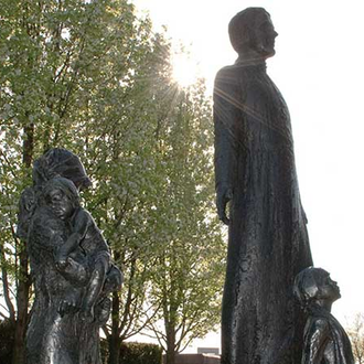 Statues of Father Michael J. McGivney, a widow and her children stand outside the Supreme Council headquarters in New Haven