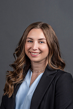 Headshot of Cara Peccerillo, who smiles while wearing a baby blue blouse and black blazer