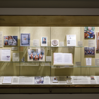 Wall case of Cause for Canonization Gallery discussing the beatification of Father Michael J. McGivney, includign the miracle healing of Michael "Mikey" McGivney Schachle. 