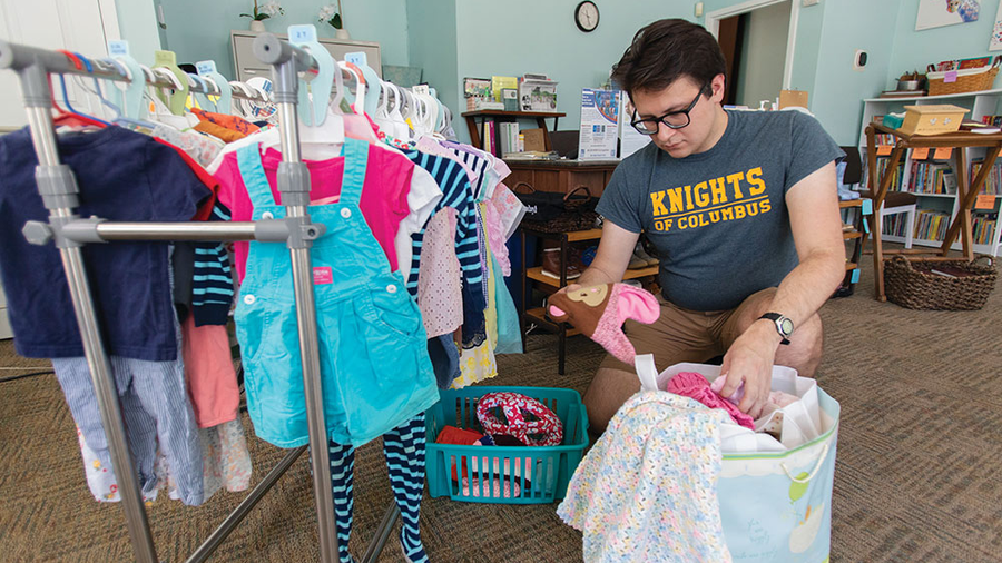 Past Grand Knight Kenneth Kovalski sorts clothing for clients of the Capitol Hill Pregnancy Center.