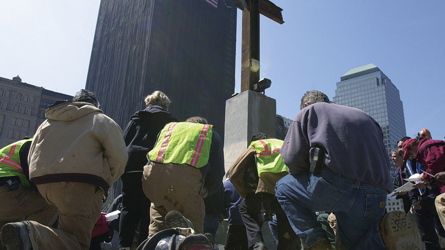 Men kneeling before World Tradw Center cross
