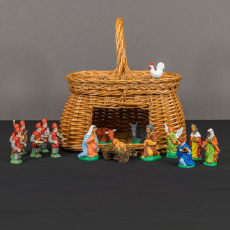 Photo of a clay Nativity scene with the Holy Family, Angel, Magi, a band, and animals. The stable is a basket.