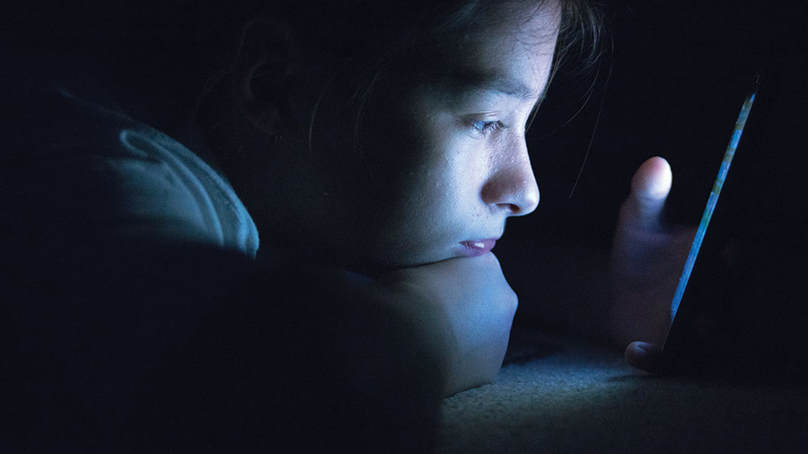 A young child staring closely at a smartphone