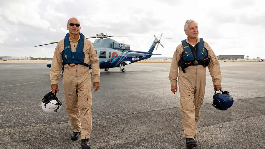 Deacon Benny Matos (left) and Anthony Marinello stand in front of the Sikorsky S-76 helicopter they flew to rescue Americans in Haiti this past March and April. (Photo by David González)