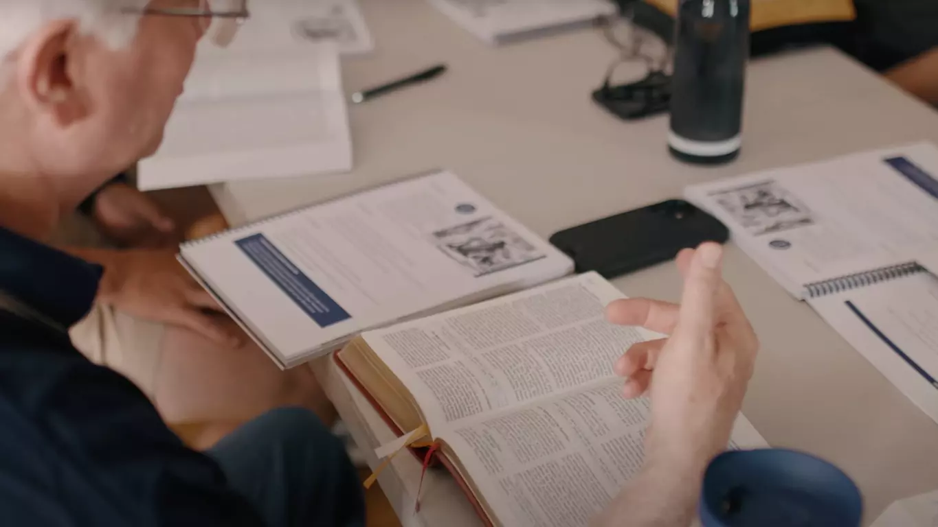 A hand running through lines in a book.