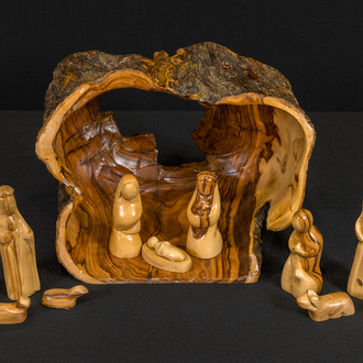 Olivewood carved Nativity with the Holy Family in a stable made from a hollowed-out log. Other figures of people and animals are outside the stable.