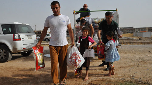 Families carry food that they received from the Knights of Columbus.
