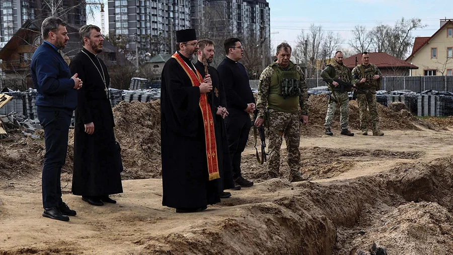 Major Archbishop Sviatoslav Shevchuk leads clergy and soldiers in prayer at a mass grave