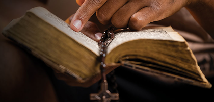 the rosary hanging from an open bible