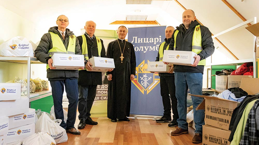 Members of Sts. Borys and Hlib Council 17740 in Fastiv, joined by their chaplain, Father Vitalii Martsyniuk, prepare care pack ages for distribution at their parish Mercy Center.