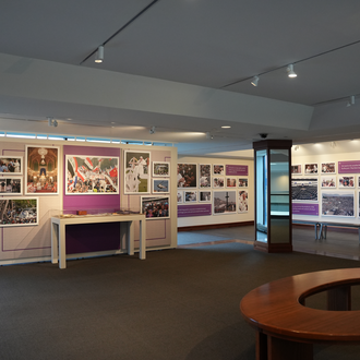 Color photo of a museum gallery with photographs and items related to Pope Francis’ international trips on exhibit.