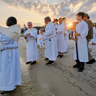 JUAN DIEGO ROUTE | Father Vincent Ajayi, parochial vicar of St. Thomas the Apostle Catholic Church in Long Beach, Miss., lifts the monstrance over the Gulf of Mexico during a “Blessing of the Sea” held June 12 as part of the Juan Diego Route of the National Eucharistic Pilgrimage. (Photo by Dan Anderson).