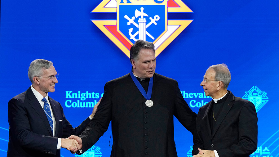 Supreme Knight Patrick Kelly and Supreme Chaplain Archbishop William Lori congratulate Father Chad Wilhelm at the awards session prior to the 142nd Supreme Convention in Québec City on Aug. 5. (Photo by Paul Haring)