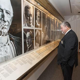 Photo of the Papal Gallery with a man in a suit looking at a case of papal medals.