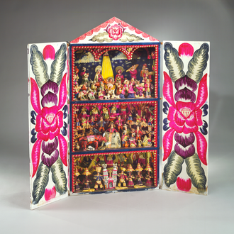 Nativity on the top shelf of 3 shelves in a potable box with doors painted with floral patterns. The other 2 shelves show scenes of Peruvian culture.