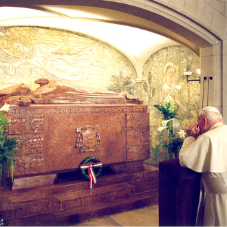 Pope John Paul II kneels in prayer before the tomb of Cardinal Mindszenty