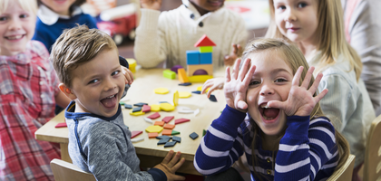 Card for Praesidium Academy with children making silly faces while playing with blocks