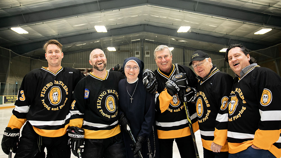 Priests dressed in hocky jersey's standing on the ice